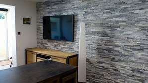 Una cocina moderna con protector contra salpicaduras de piedra, un televisor de pantalla plana montado sobre la encimera y un refrigerador a la derecha.
