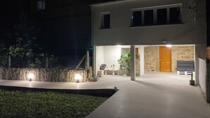 A modern two-story house with a stone facade, a wooden door, and a well-lit entrance.