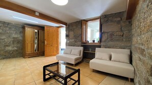 A living room with a stone wall, a wooden wardrobe, a glass coffee table, and two white sofas.