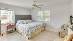 Une chambre à coucher avec un lit, une table de chevet, une lampe et un ventilateur de plafond.
