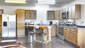 Una cocina con armarios de madera, electrodomésticos de acero inoxidable y una barra con taburetes.