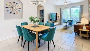 Ein modernes Wohnzimmer mit Essbereich, großem Fernseher und Balkon mit Blick.
