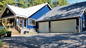 Une maison à deux étages, avec une façade bleue, un porche couvert et deux portes de garage.
