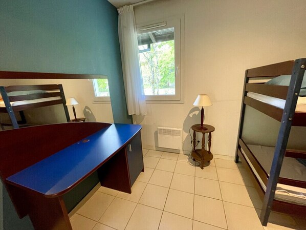 A dormitory room with bunk beds, a desk, a chair, a lamp, and a window. - Maison Bruyères by Agence Bru - 483473 (Lacanau)