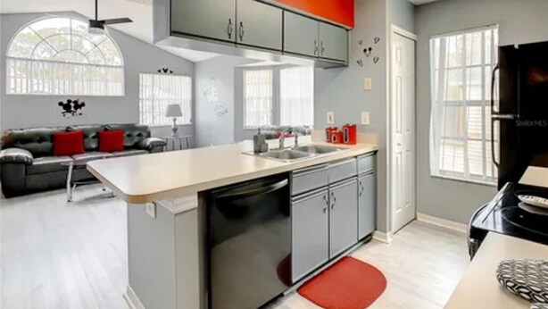 A modern kitchen with grey cabinets, a white countertop, and a red accent wall. - Disney Themed Condo mins from Disney attractions (Kissimmee)
