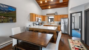 A modern kitchen with wooden cabinets, a central island, and a stainless steel refrigerator. - Incredible Ski-Access: 3 Bed Chalet with HotTub (Big Sky)