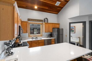 A modern kitchen with wooden cabinets, stainless steel appliances, and a white countertop.