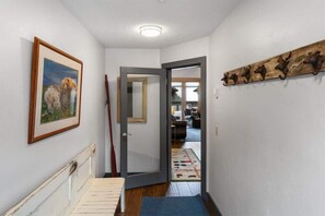 Käytävä, jossa on puinen ovi, seinällä oleva kehystetty taulu ja maalaishenkinen seinäkoriste.