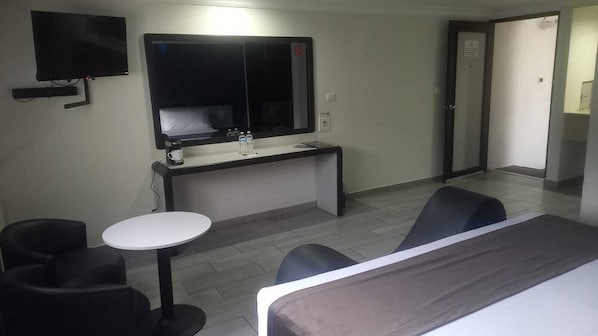 A hotel room with a bed, a desk with a mirror, a small round table, two chairs, and a TV. - Real la Viga Motel (Mexico City)