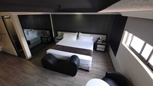 Een moderne hotelkamer met een groot bed, een zithoek, een klein tafeltje en een raam voor natuurlijk licht.