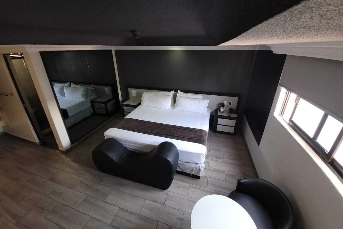 Een moderne hotelkamer met een groot bed, een zithoek, een klein tafeltje en een raam voor natuurlijk licht.