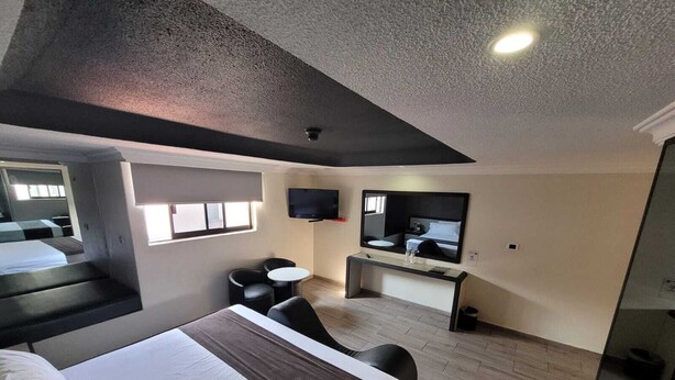 Een moderne hotelkamer met een bed, een bureau met spiegel, een televisie en twee stoelen.