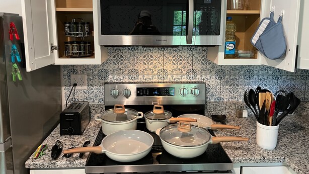 Una cocina con un microondas de acero inoxidable, una estufa con ollas, un tostador y un esclavo de especias.