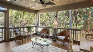 A spacious veranda with a glass table, wicker chairs, and a ceiling fan. - Pets  Considered, Community Pool, Lagoon View, Golf Cart Included 875 Salt Cedar Lane (Fripp Island)