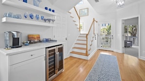 Een moderne keuken met witte kasten, een koffieapparaat en blauw decoratief glaswerk op planken.