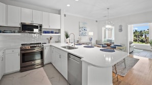 Een moderne keuken met witte kasten, roestvrijstalen apparatuur en een groot eiland met blauwe decoratieve borden.