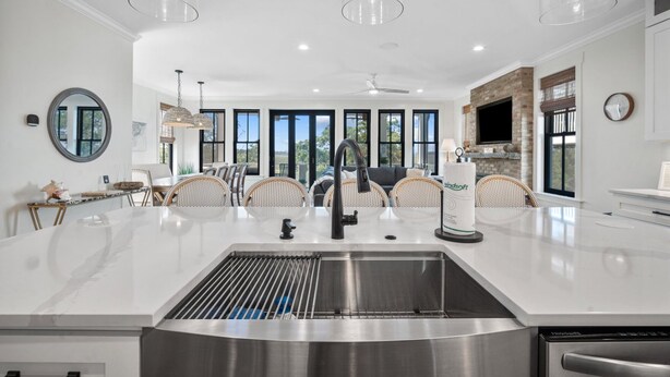 A modern kitchen with a large island, stainless steel appliances, and a view of the outdoors. - Shuck Yeah - Brand New, Panoramic Marsh and Golf Views, Golf cart included 92 Davis Love (Fripp Island)