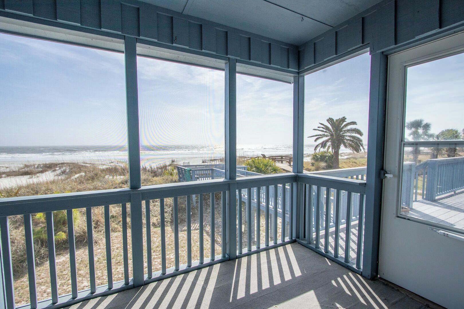 A covered balcony with a view of the beach and ocean.