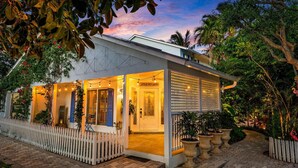 A modern house with a white exterior, a covered porch, and a sign reading "Little Key West."