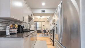 A modern kitchen with stainless steel appliances, a built-in oven, and a dining area with a table and chairs. - Cozy Oasis Apt - In Med Center & NRG (Houston)