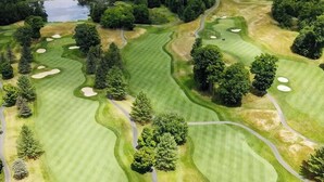 Vista aérea de un campo de golf con múltiples búnkeres, árboles y un cuerpo de agua.