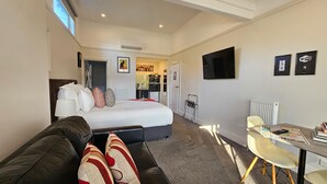 Una habitación de hotel con cama, sofá, escritorio y televisor.