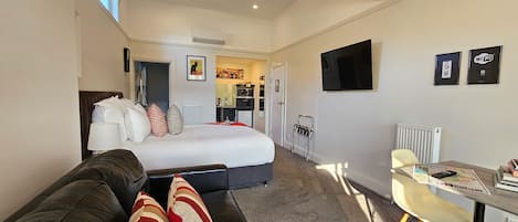 Una habitación de hotel con cama, sofá, escritorio y televisor.