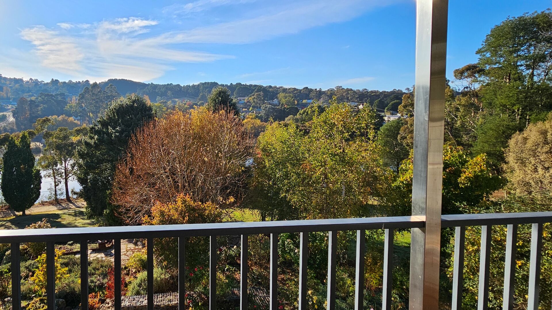 A balcony with a view of a forested landscape and a distant hill.