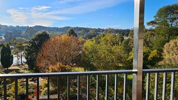 A balcony with a view of a forested landscape and a distant hill.