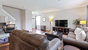 Een woonkamer met een bank, een salontafel, een televisie en een lamp.