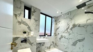A modern bathroom with a marble wall, a toilet, a sink, and a shower. - Massive 3 bedroom - Ground Floor - Near the Beach! (Bournemouth)