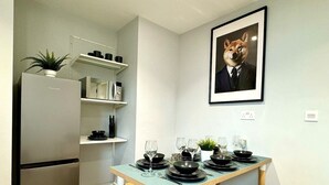 A modern kitchen with a built-in refrigerator, wooden dining table set with black plates and glasses, and a framed picture of a dog on the wall. - Massive 3 bedroom - Ground Floor - Near the Beach! (Bournemouth)