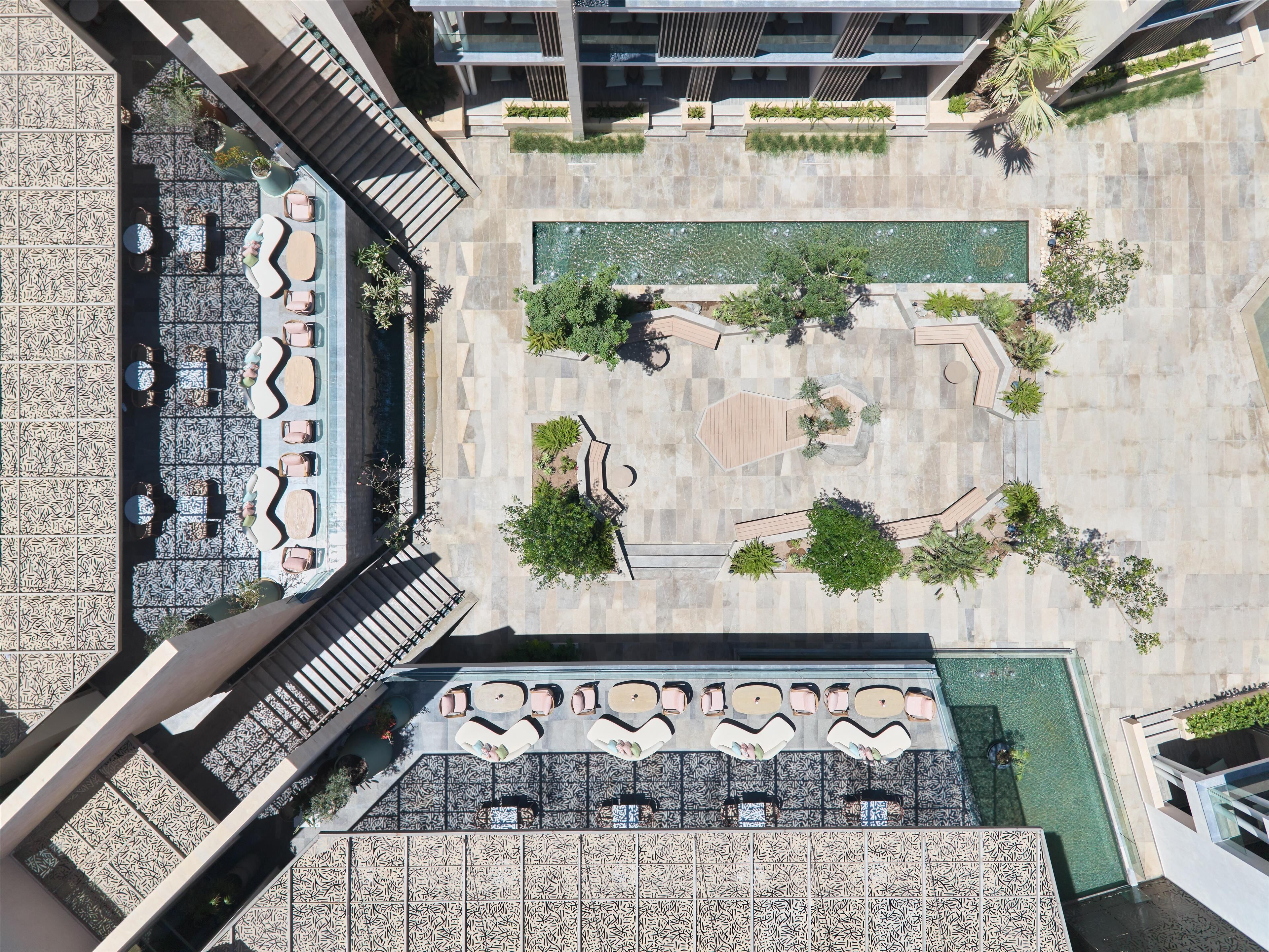 Vista aérea de una terraza en la azotea con mobiliario exterior, piscina y vegetación circundante.