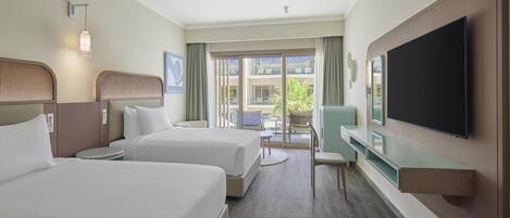 Habitación de hotel con dos camas, televisión, escritorio y vistas al exterior.