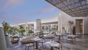 Un espace extérieur aménagé pour les repas, avec des tables et des chaises, une piscine et une vue sur les bâtiments en arrière-plan.