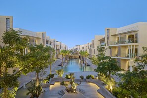 Un complexe hôtelier doté d’une piscine centrale, de nombreux balcons et d’un aménagement paysager luxuriant.