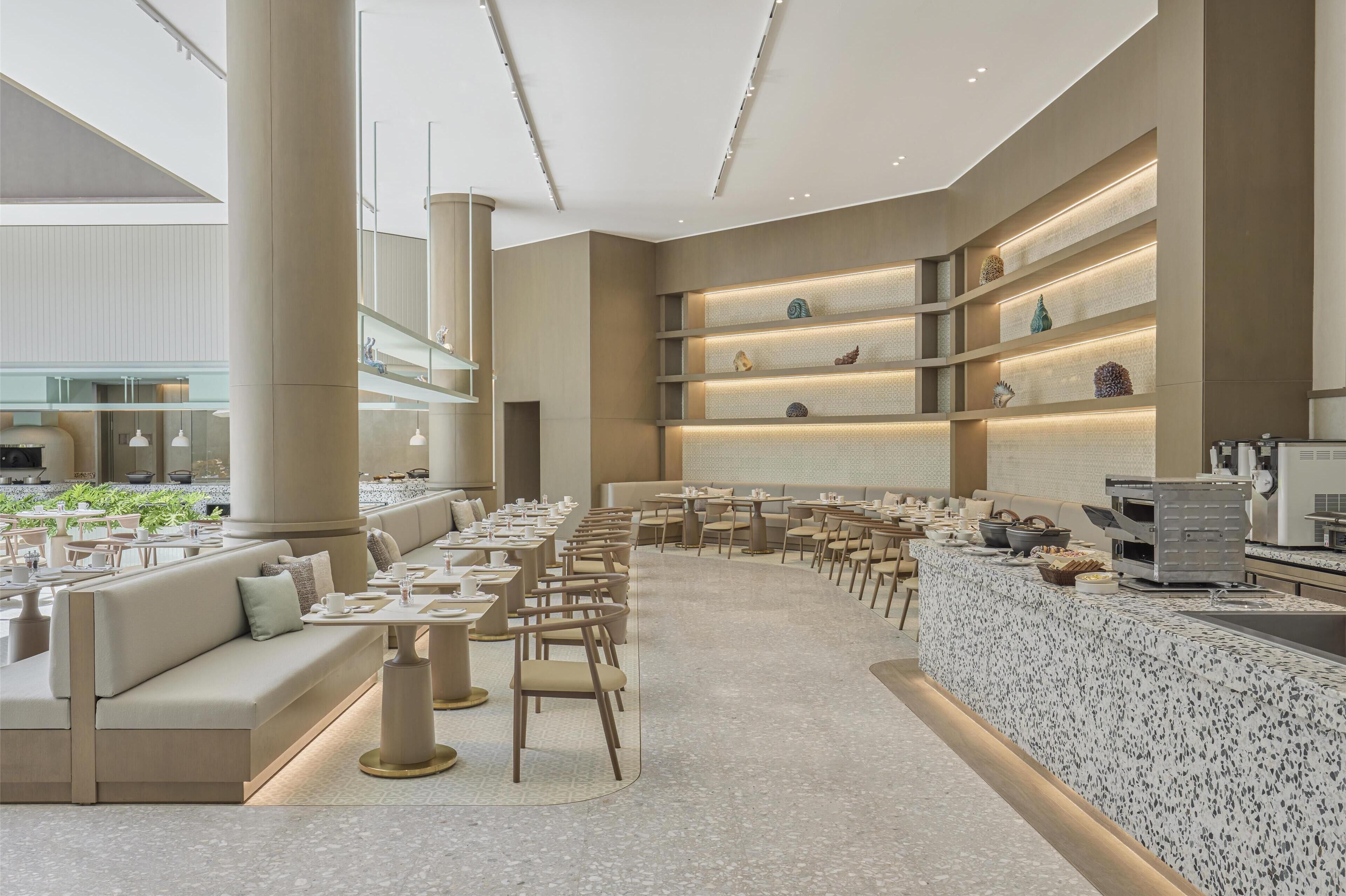A modern dining area with a long counter, multiple seating options, and decorative shelves.