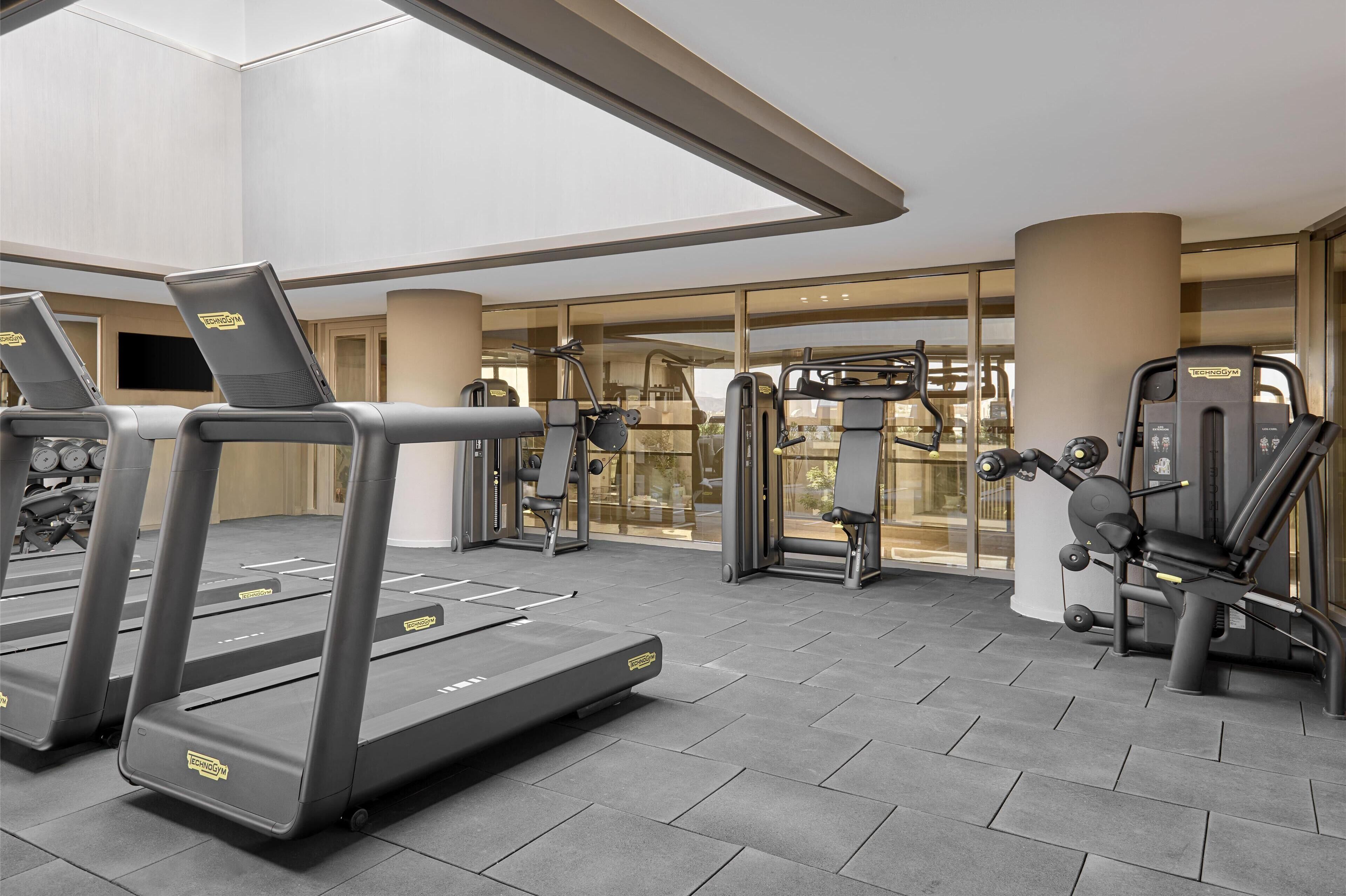 Un gimnasio moderno con cintas de correr, máquinas de pesas y un amplio ventanal.