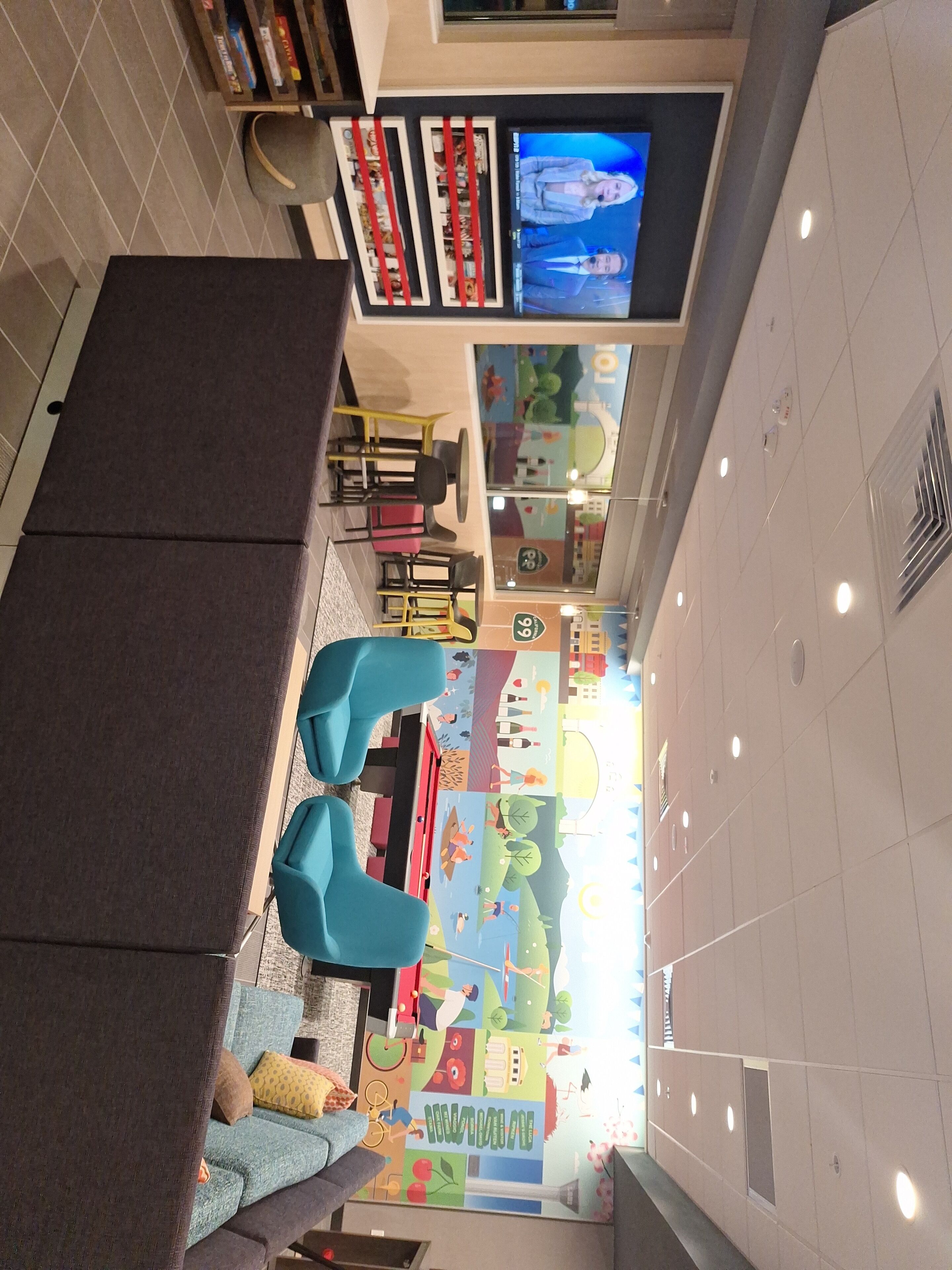 A children's play area with colorful murals, seating, and a television screen.