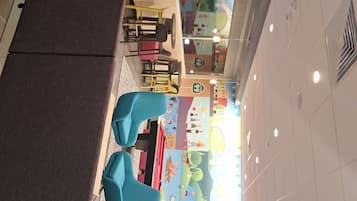 A children's play area with colorful murals, seating, and a television screen.
