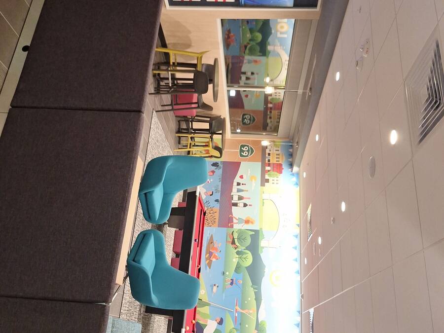 A children's play area with colorful murals, seating, and a television screen.