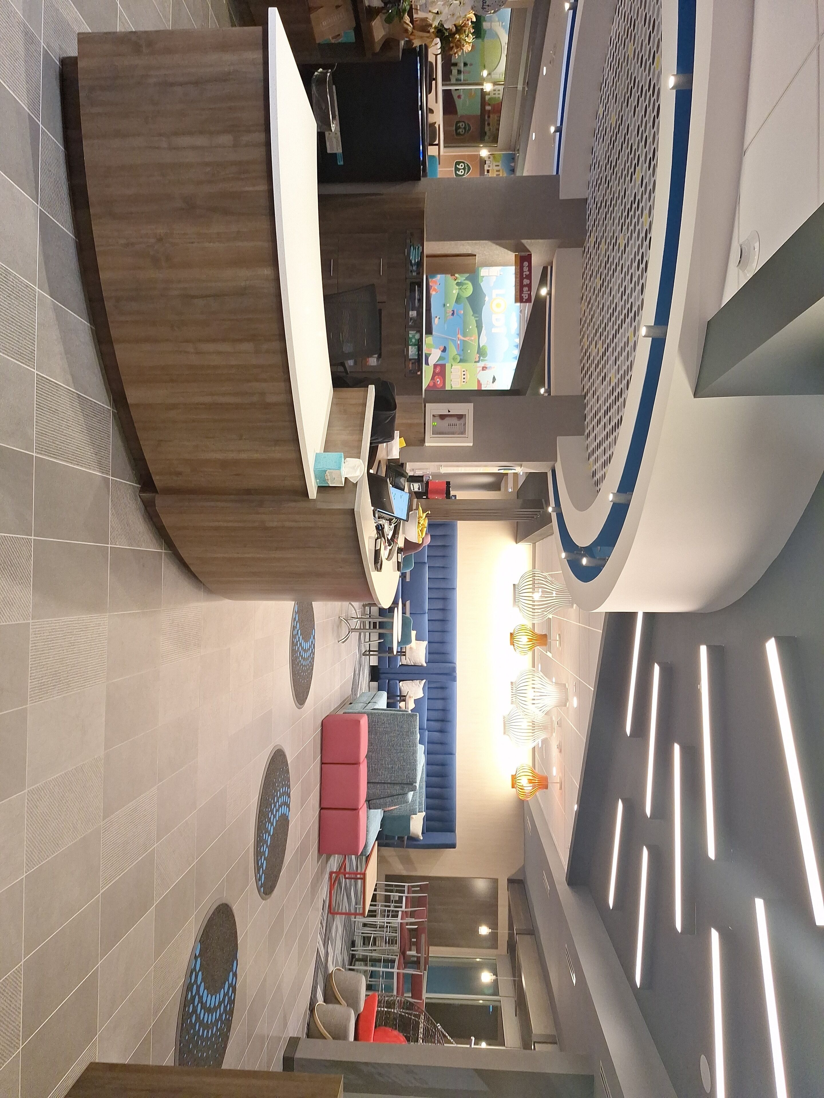 A modern hotel lobby with a reception desk, seating area, and a large window.