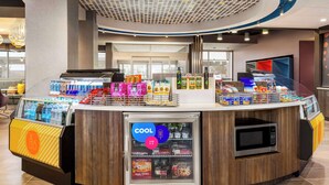 A self-service kiosk with a refrigerated section, microwave, and various packaged food items. - Tru By Hilton Lodi (Lodi)