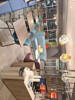A modern hotel lobby with a seating area featuring blue sofas and wooden tables. There are decorative lamps and a reception desk with a coffee machine.