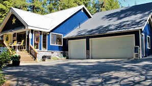 Een tweelaags huis met een garage, een overdekte veranda met stoelen en een sterdecoratie op het dak.