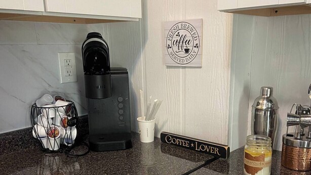 A kitchen with a coffee maker, a coffee cup holder, a jar of coffee creamer, and a sign that says "Coffee Lover".