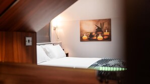 A bedroom with a bed, a nightstand, a wall-mounted light, and a painting of candles and stones. - Annex, 2 Bed, Sleeps 4, Parking (Ossett)