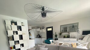Una sala de estar moderna con un sofá gris, una mesa de centro y un ventilador de techo original.