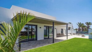A modern house with a covered patio, a swimming pool, and a well-maintained lawn. - Villa Tirma by Villa Plus (Playa Blanca)