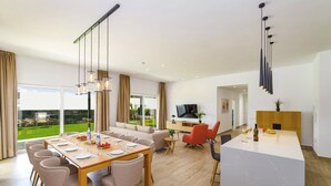 A spacious living area with a dining table, sofas, and a kitchen area. - Villa Tirma by Villa Plus (Playa Blanca)